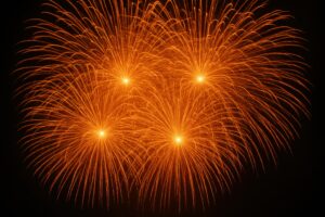 鮮やかな橙色の花火が4発開く夜空