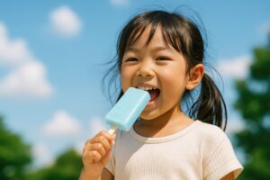 アイスを頬張る笑顔の女の子と青空