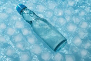 氷と水に浮かぶ冷えたラムネ瓶