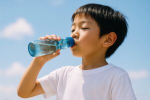 青空の下でラムネを飲む男の子