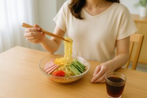 ガラスの器で冷やし中華を食べる女性の手元