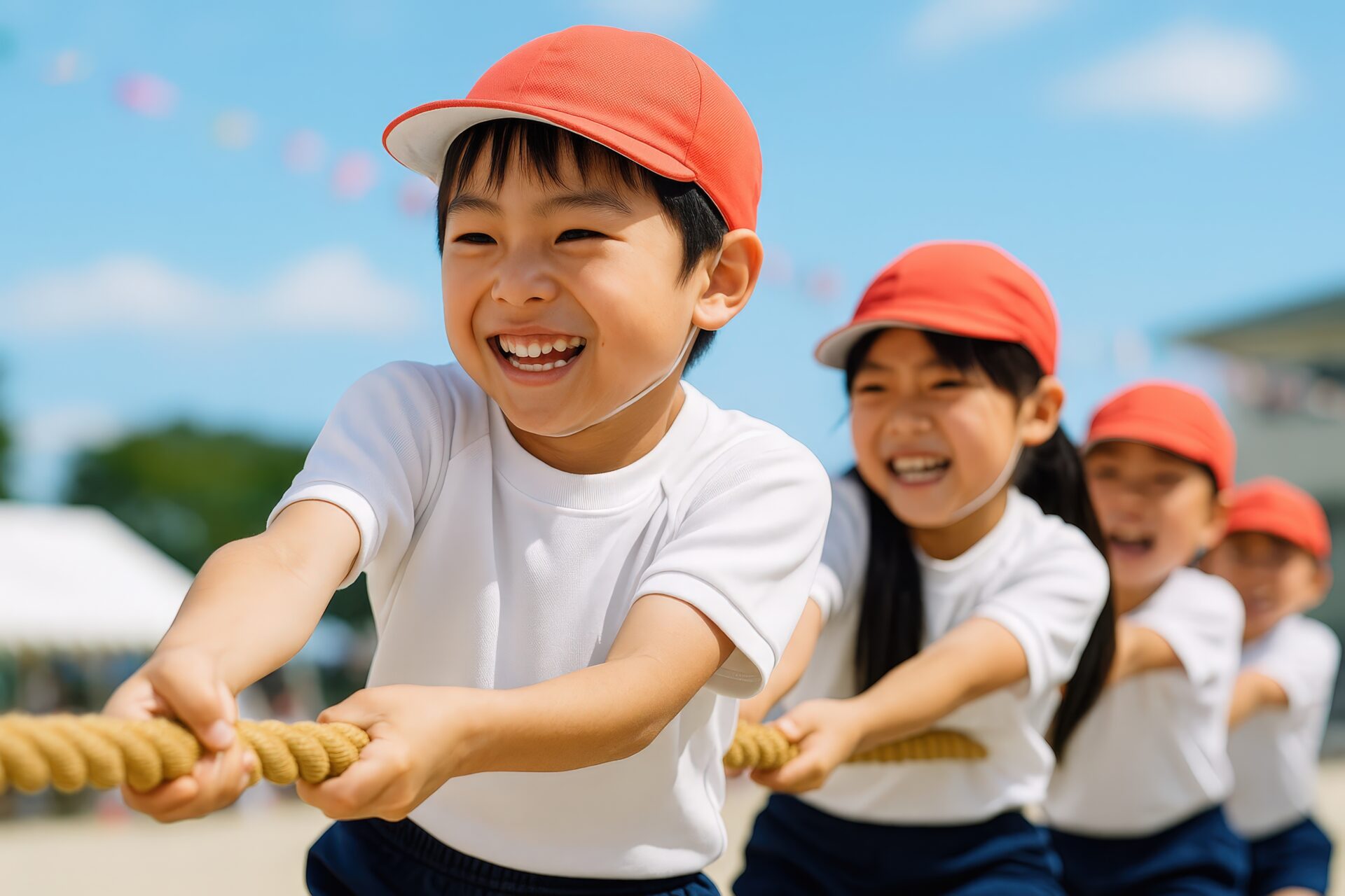 綱引きを楽しむ赤い帽子の小学生たち