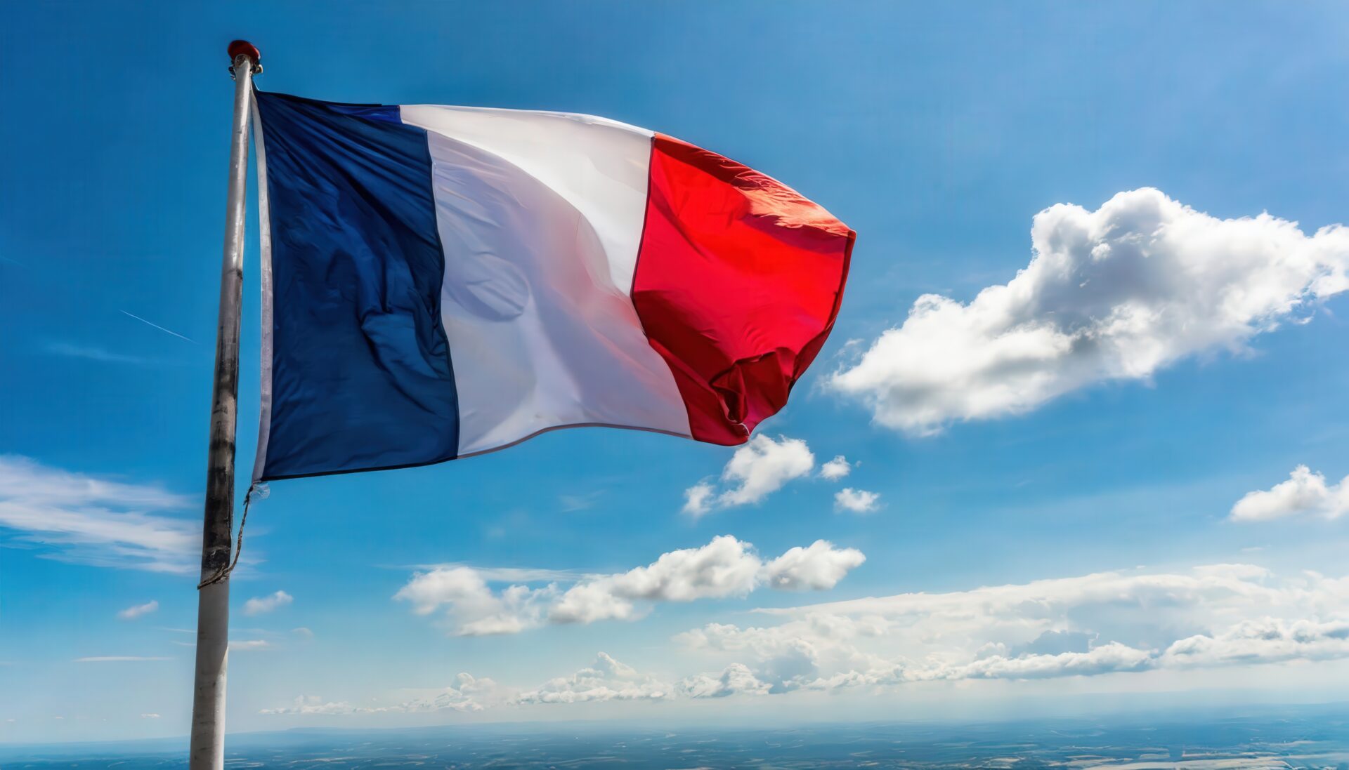 フランス国旗が青空と雲の中でなびく