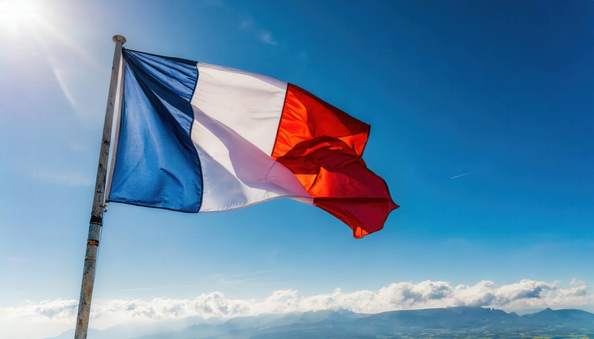 フランス国旗が山と空を背景に掲げられている