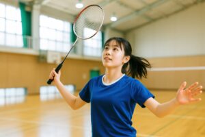 シャトルを見ながら構える笑顔の女子学生