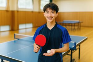 卓球ラケットとボールを持って立つ男子学生