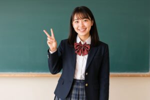 教室でピースサインをする笑顔の女子高校生