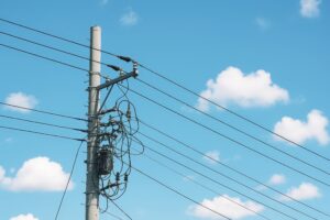 青空に浮かぶ雲と電線が交差する電柱