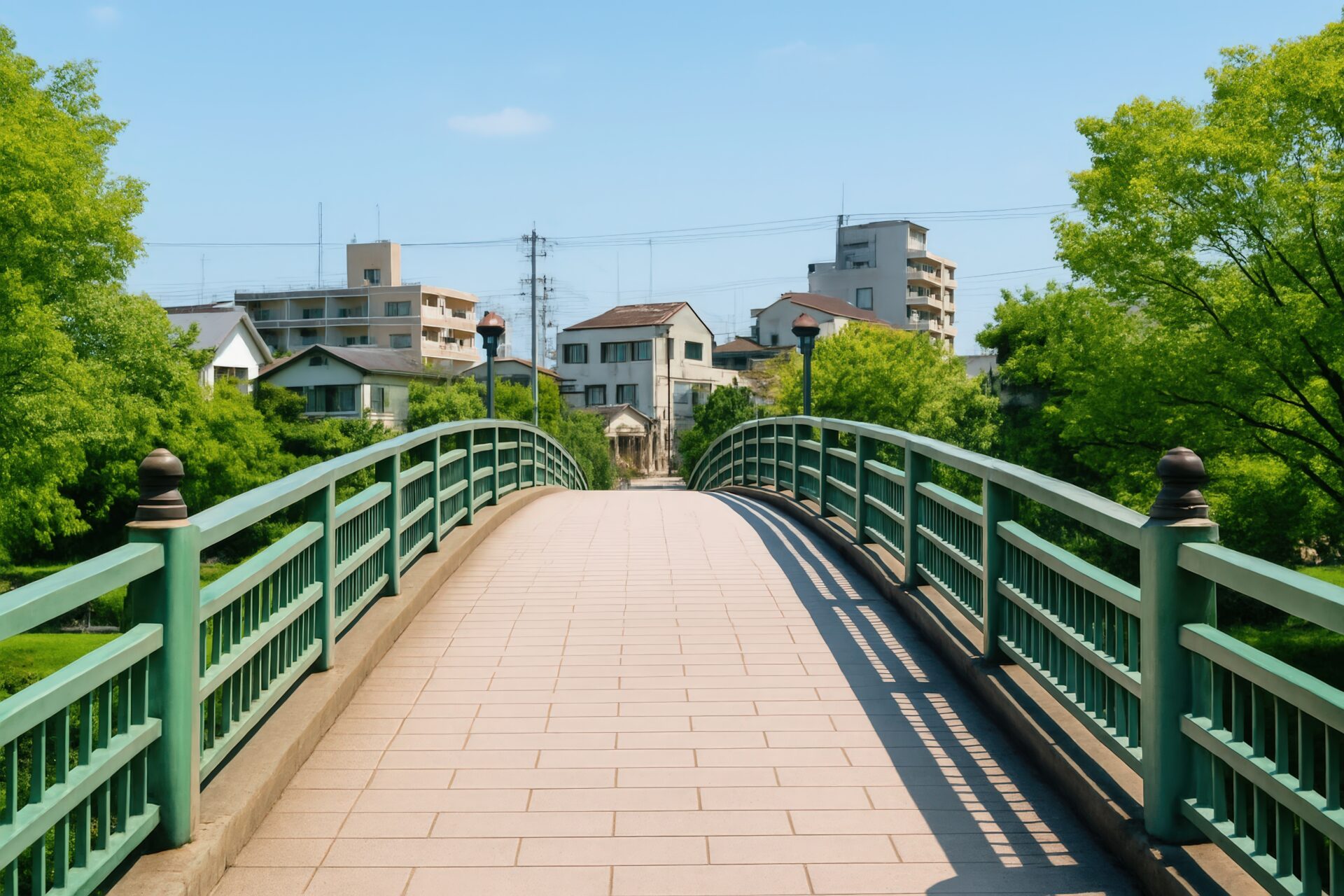 緑の手すりがある歩道橋と住宅街の風景