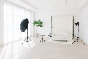 白い背景紙と照明機材が設置された明るいスタジオ