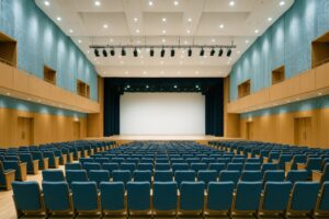 青い座席が並ぶ市民ホールのステージ全景