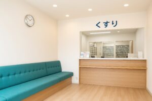 木目調カウンターとソファがある薬局の待合室