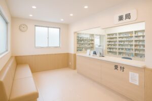 白壁と木製カウンターの調剤薬局内観