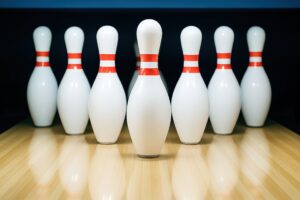 暗い背景に浮かび上がるボウリングピンの整列