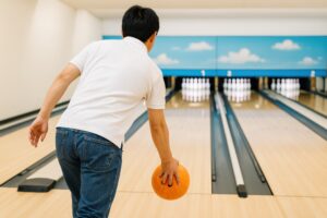 オレンジのボールを投げる白シャツの男性