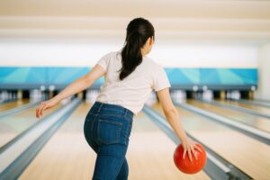 レーンに向かって投球する若い女性の後ろ姿