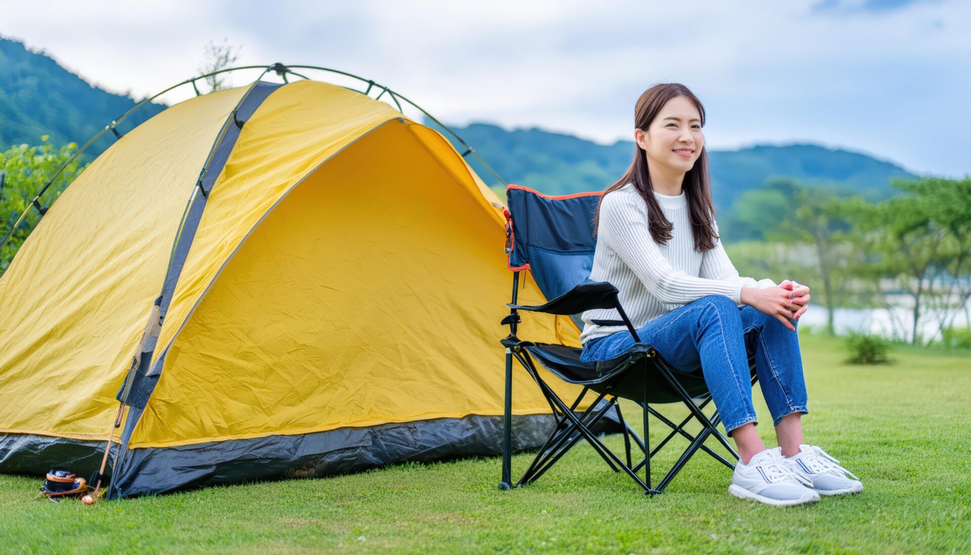 キャンプ場で黄色いテントの前に座る女性
