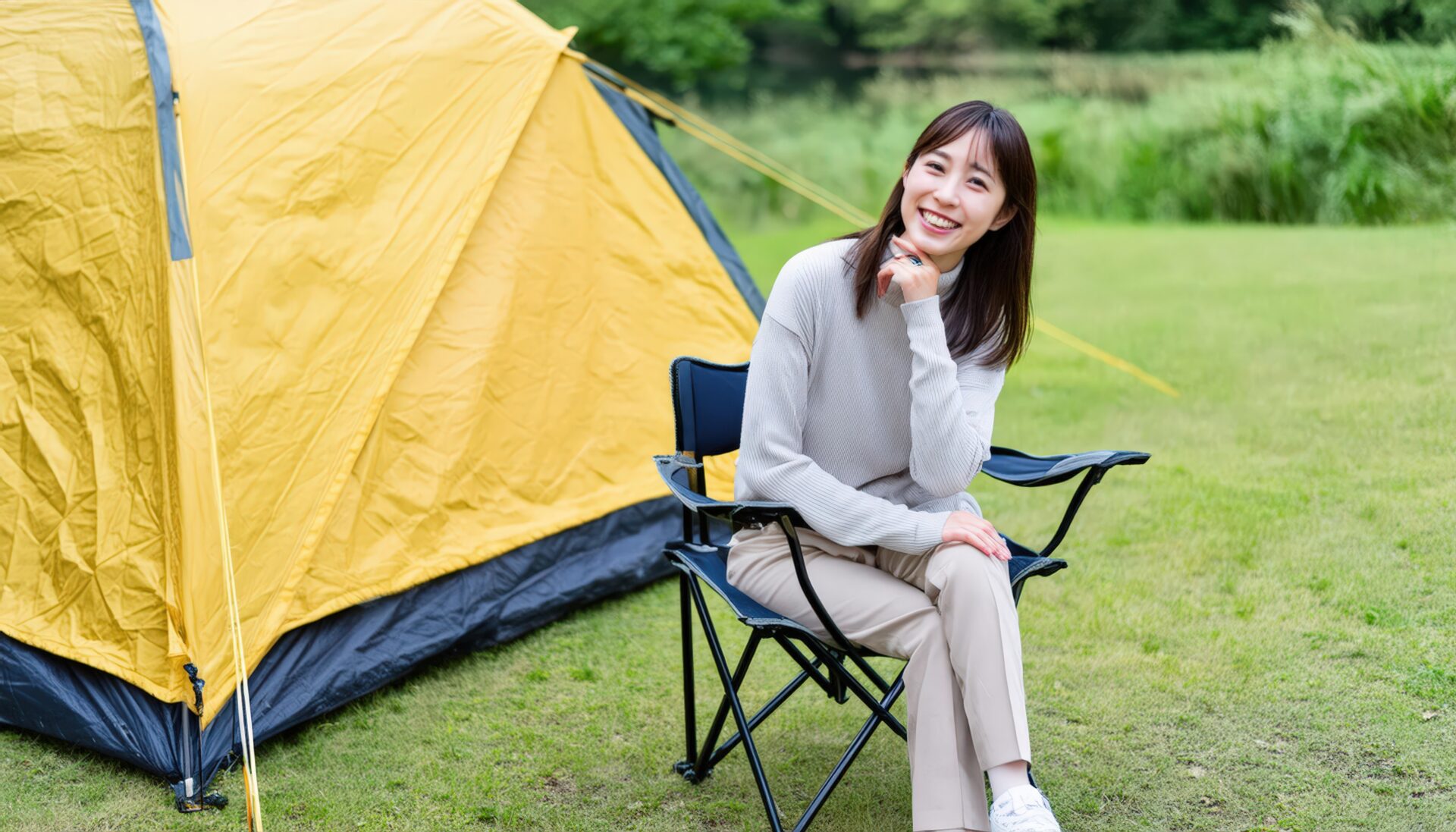 キャンプ場で微笑む女性と黄色いテント
