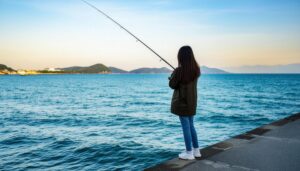 海辺の防波堤で釣りをする女性