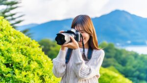 山を背景にカメラを構える笑顔の女性