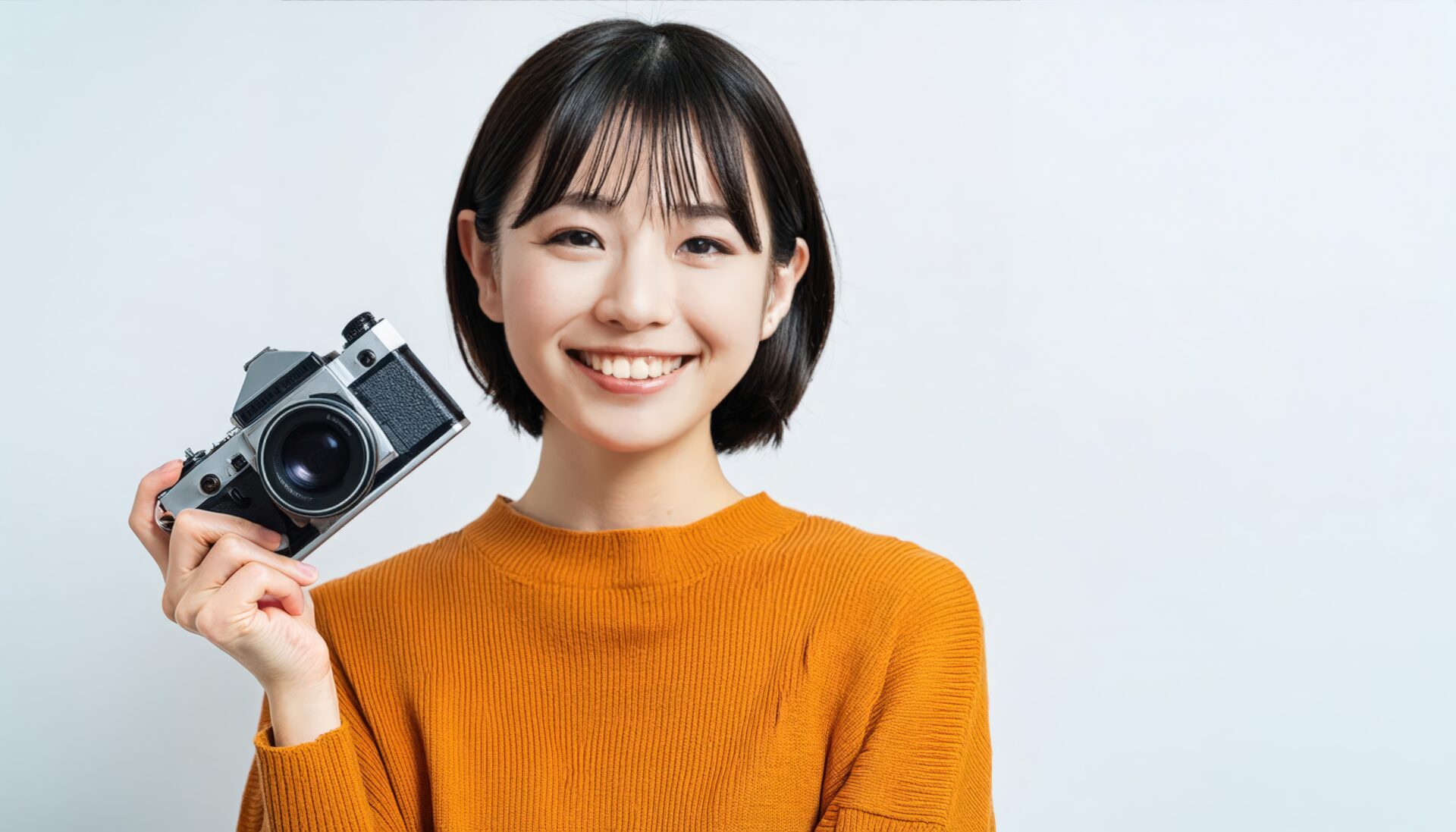 カメラを持って笑顔の女性（オレンジの服）