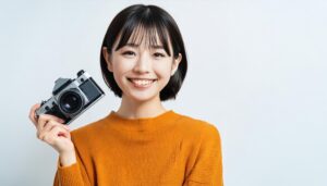 カメラを持って笑顔の女性（オレンジの服）