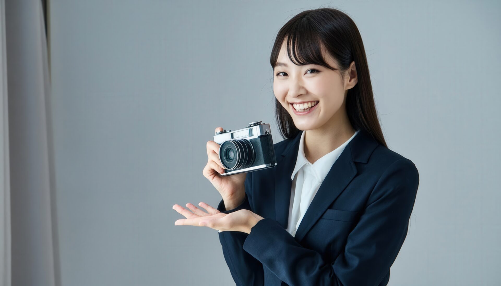 カメラを持って笑顔の女性（スーツ姿）