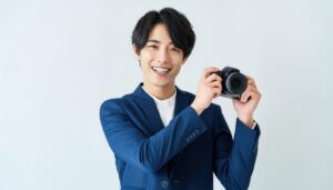 カメラを持って笑顔の男性（スーツ姿）