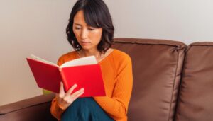 赤い本を読む女性（オレンジセーター）