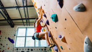 ボルダリングをする女性（室内、赤いトップス）