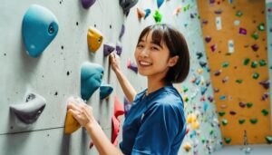 ボルダリングをする女性（室内、青いトップス）