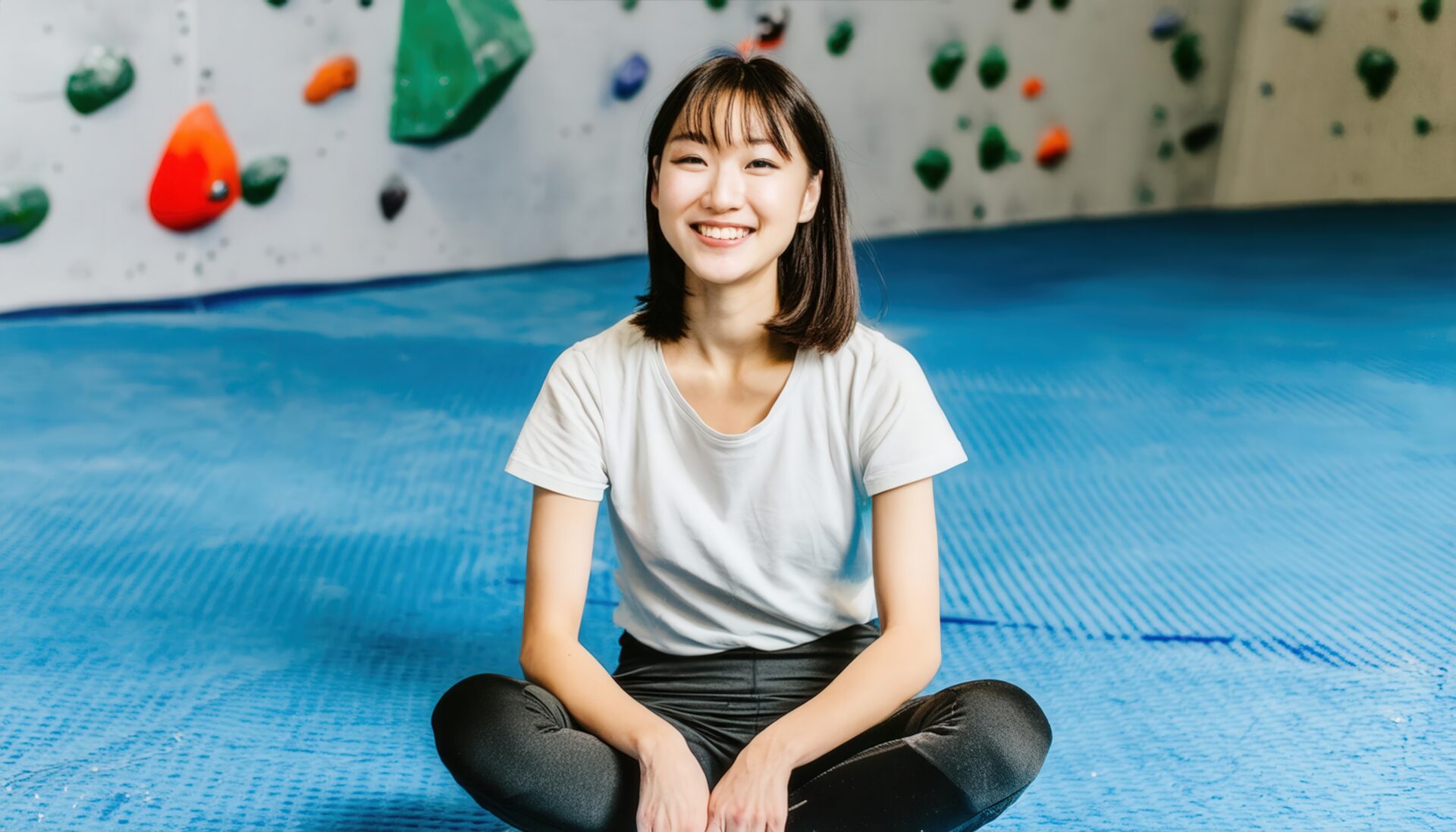 笑顔でボルダリングを休憩中の女性