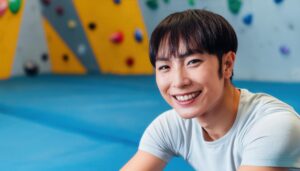 ボルダリングウォール前で笑顔の男性