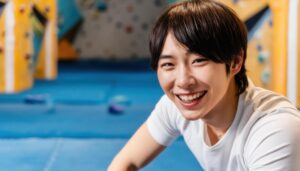 ボルダリングウォールで微笑む男性