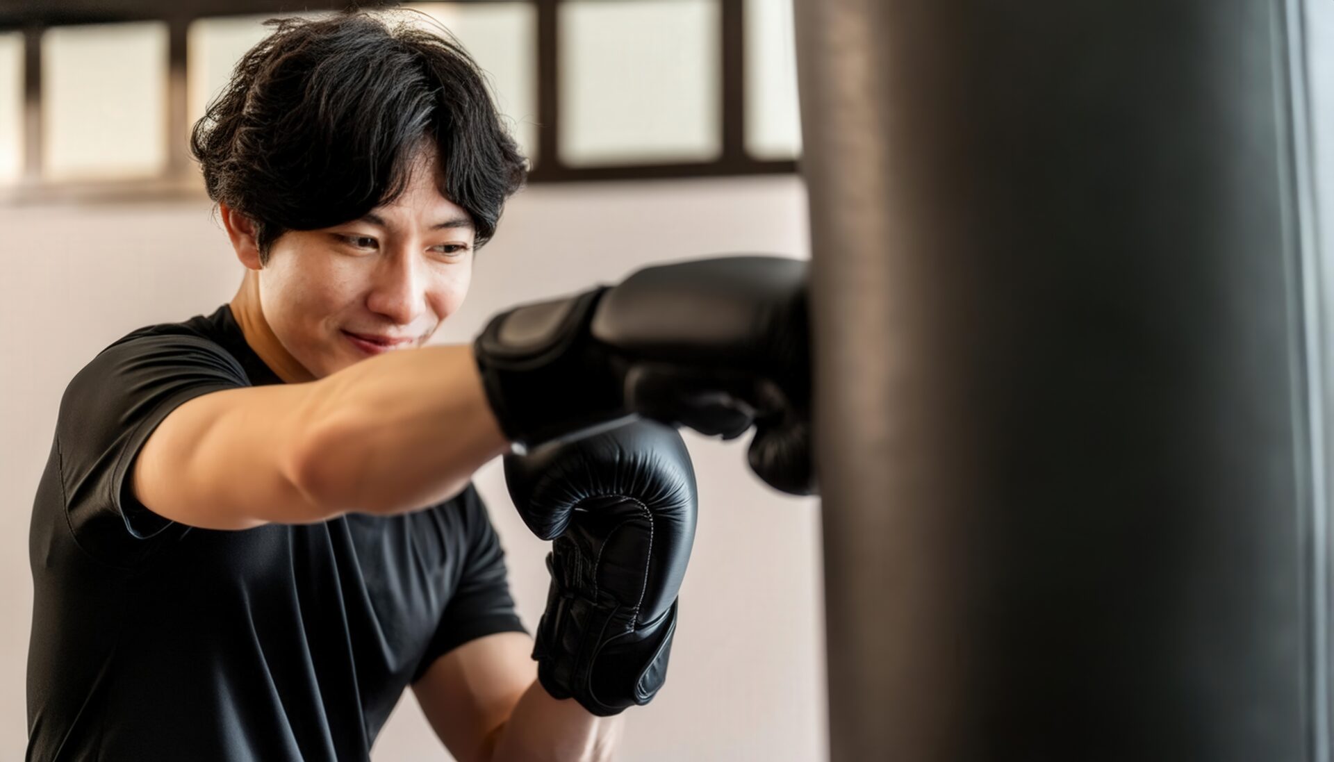 ボクシンググローブを着けてサンドバッグにパンチする男性