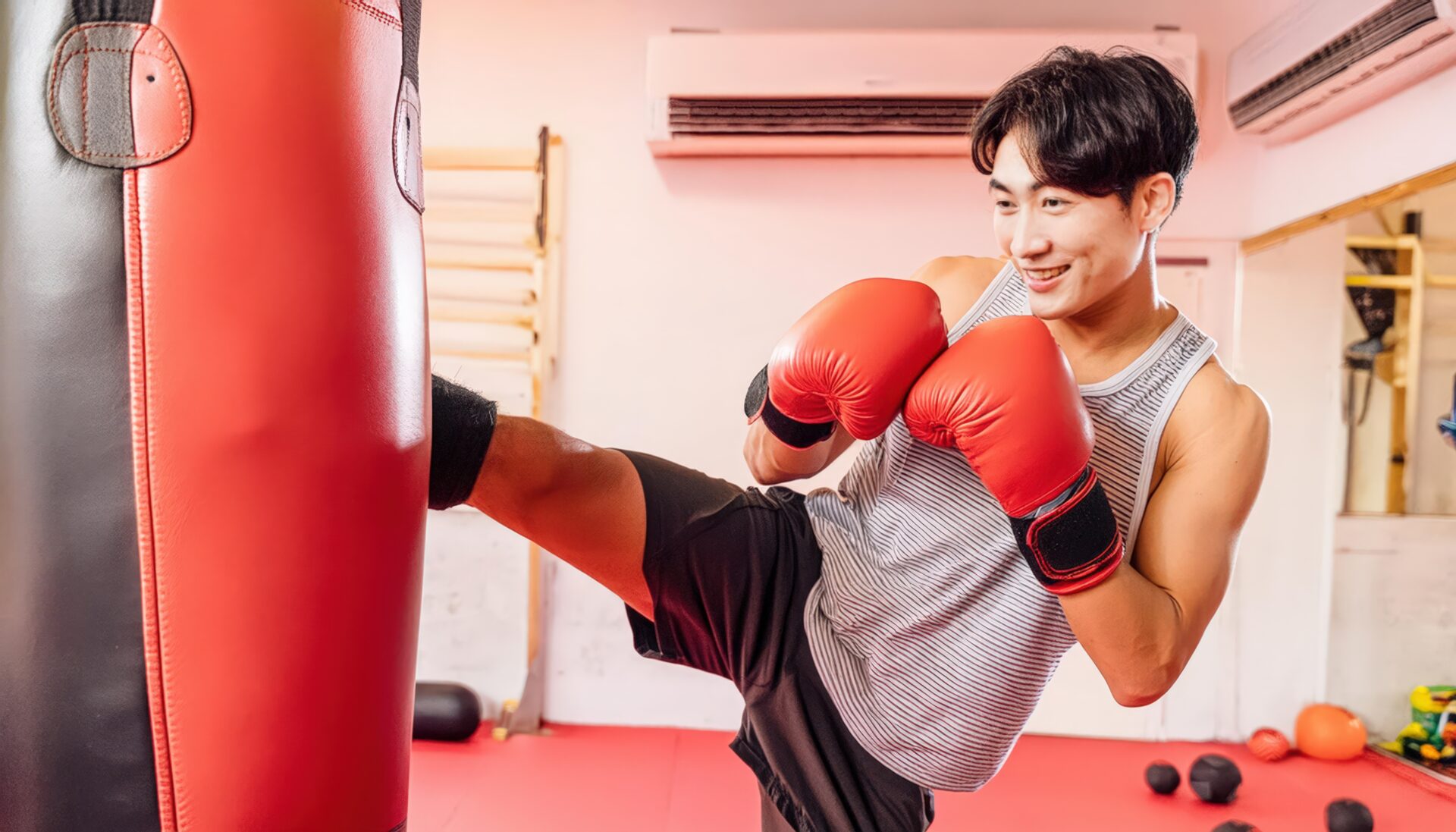 サンドバッグを蹴る笑顔の男性