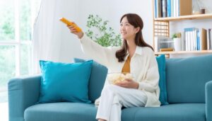 リモコンとポップコーンを持つ笑顔の女性