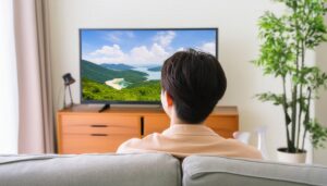 テレビで山と海の風景を観る男性