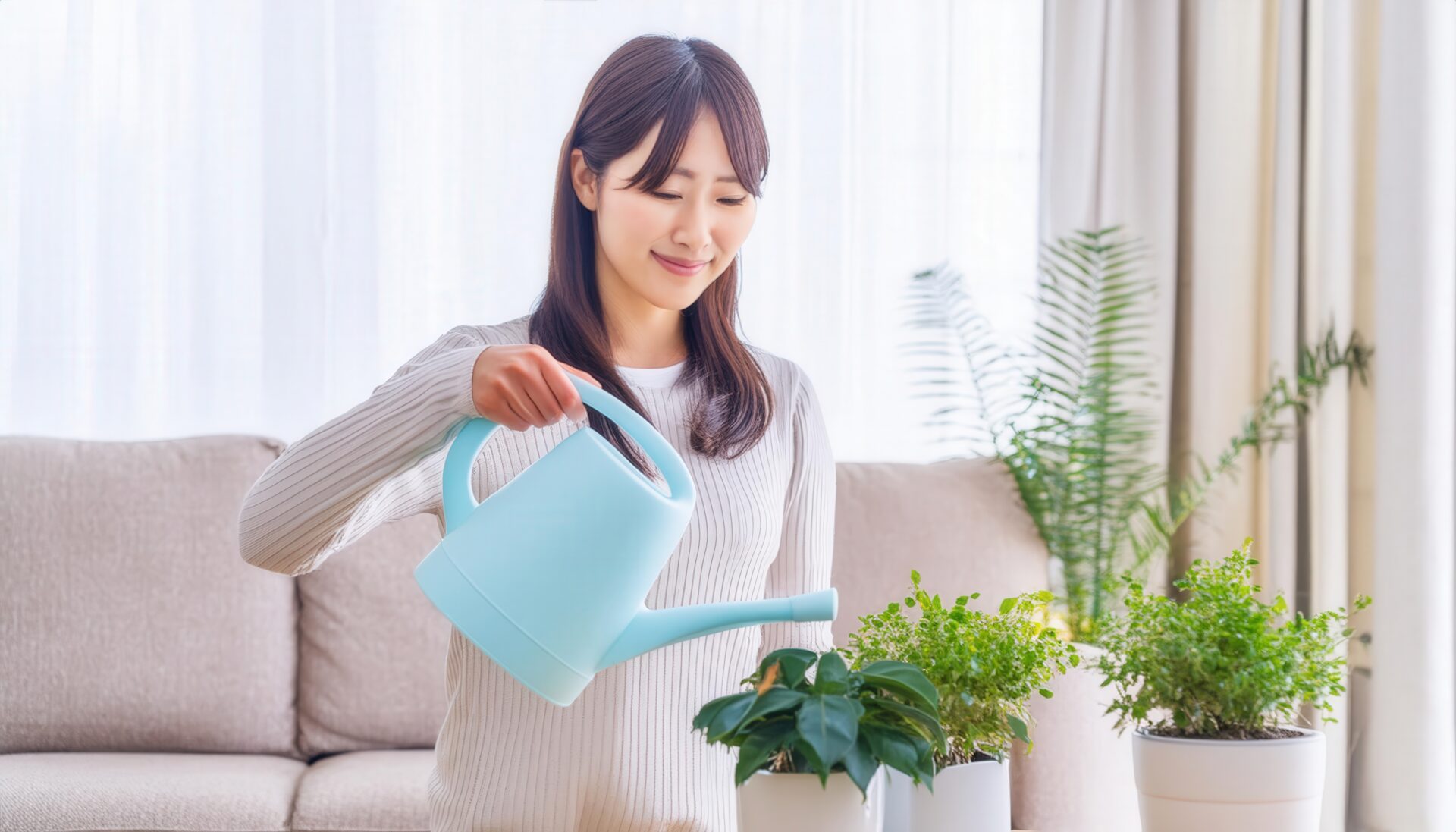 青いジョウロで観葉植物に水をやる女性