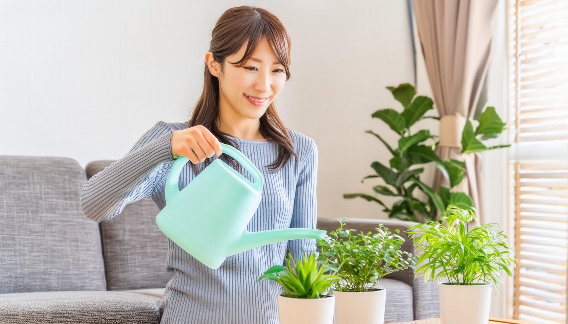 リビングでジョウロを使い植物を育てる女性