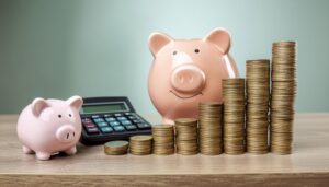 大小二つの貯金箱と右肩上がりの硬貨と電卓