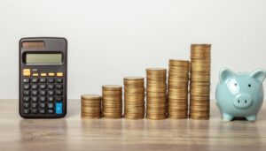 水色の貯金箱と六つの硬貨の山と電卓