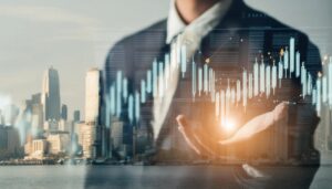 都市の景観と株価チャートを背景にビジネスパーソン