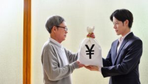 相続を渡す老年の男性とカーディガン姿の息子