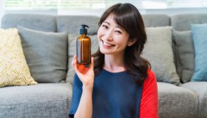 笑顔で化粧水・美容液のボトルを持つ女性