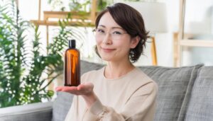 化粧水・美容液のボトルを持つ眼鏡の女性