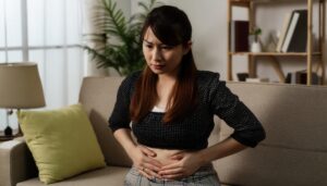 暗い部屋でお腹を押さえる女性
