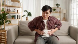 ソファでお腹を抱える男性