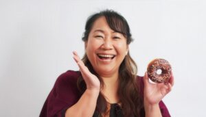 ドーナツを持つ笑顔の女性