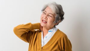 首を押さえる高齢女性